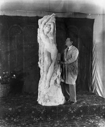 Sculptor poses by work