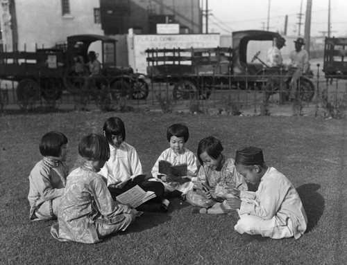 Chinese chidren sitting on the grass reading