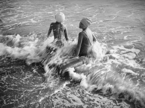 Two girls splashing water at the beach