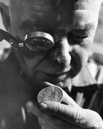 Coin shop owner Floyd Mars inspects 1886 silver dollar