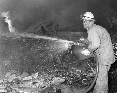 Fireman sprays hot debris of crash at 12036 Vose St. in aftermath of plane accident