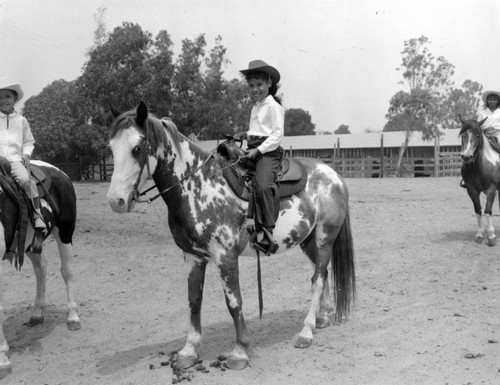 Unidentified young girls ride horseback