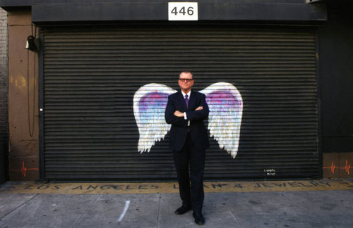 Hal Bastian posing in front of a mural depicting angel wings