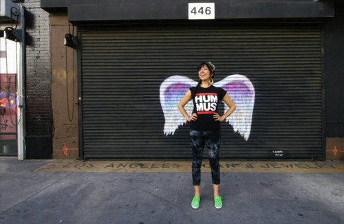 Unidentified woman posing in front of a mural depicting angel wings