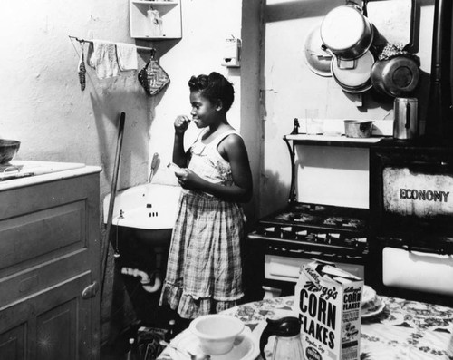 Girl brushes teeth in kitchen, slum dwelling