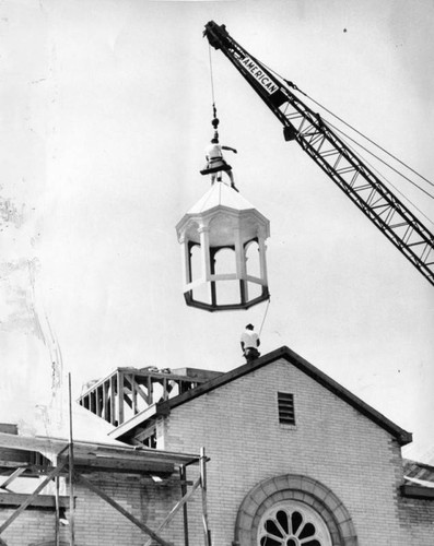 Crane lifts dome out of church and onto roof