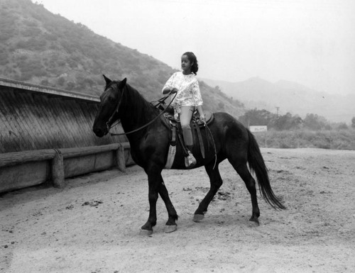 Unidentified young girls ride horseback