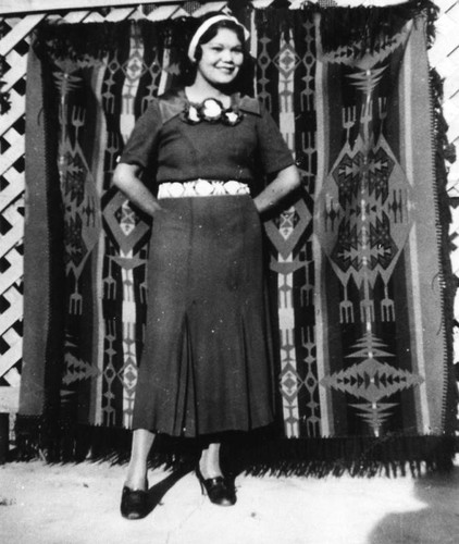 American Indian girl standing in front of blanket