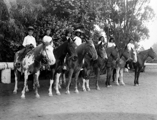 Unidentified young girls ride horseback