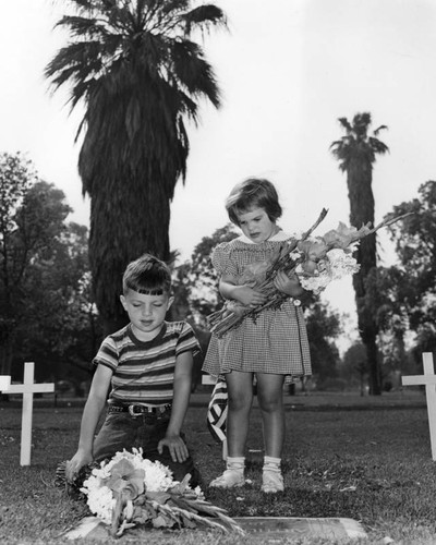 Children placing flowers on a grave