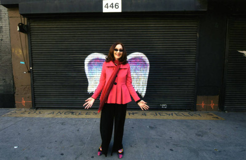 Unidentified woman with a red scarf posing in front of a mural depicting angel wings