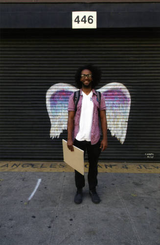 Unidentified man posing in front of a mural depicting angel wings