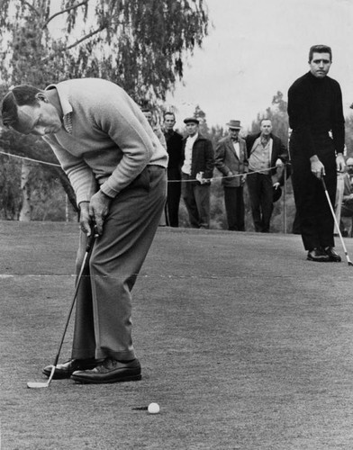 Arnold Palmer putts while Gary Player looks on at Rancho