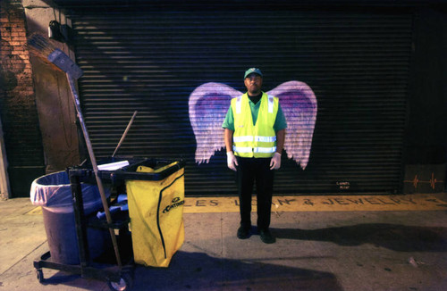 Unidentified janitorial staff posing in front of a mural depicting angel wings