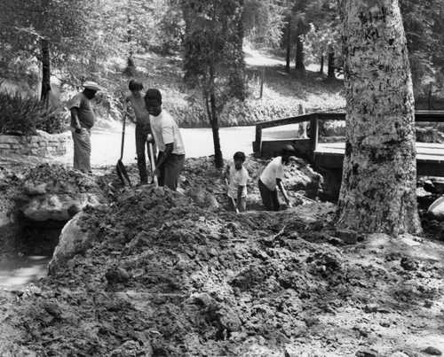 Youth corpsmen shoveling mud