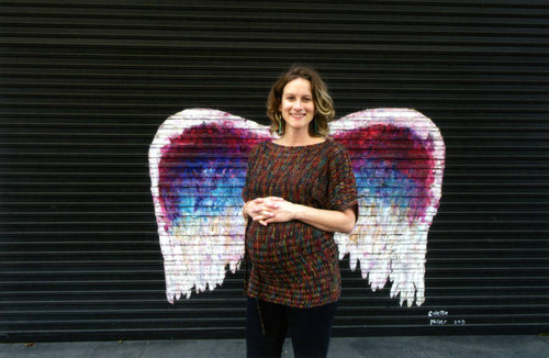 Unidentified woman posing in front of a mural depicting angel wings