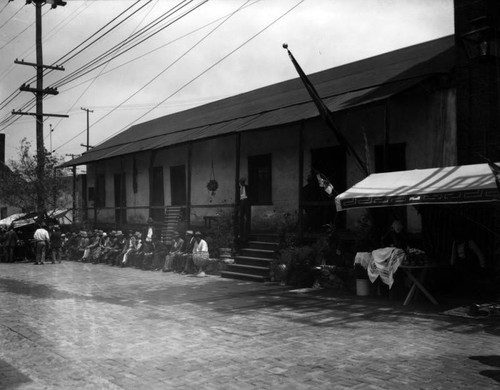 Avila Adobe, numerous men sit along the front porch