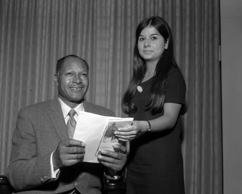 Councilman Tom Bradley holding a campus guide brochure