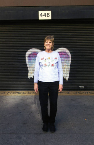 Unidentified woman posing in front of a mural depicting angel wings