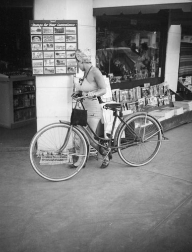 Woman with bike in front of the Palm Springs Drug and Import Company