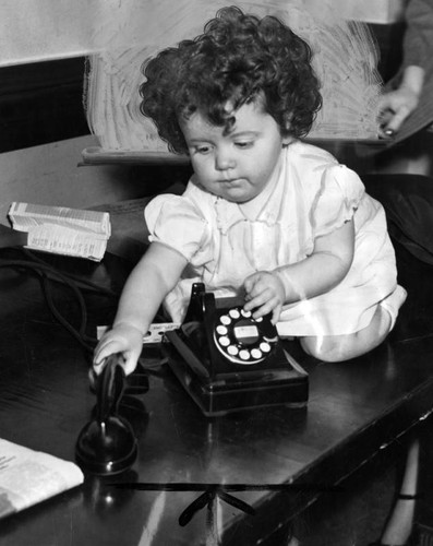 Little girl plays with a telephone