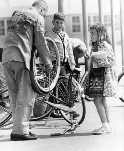 Optimist inspecting bicycle for student