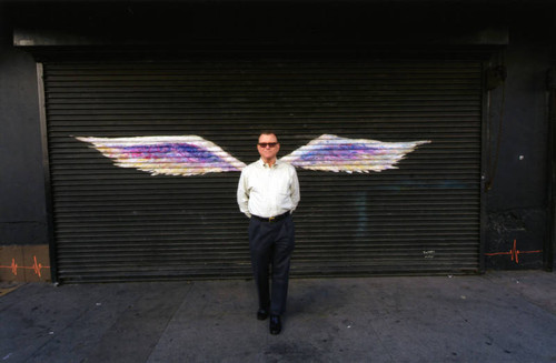 Hal Bastian posing in front of a mural depicting angel wings