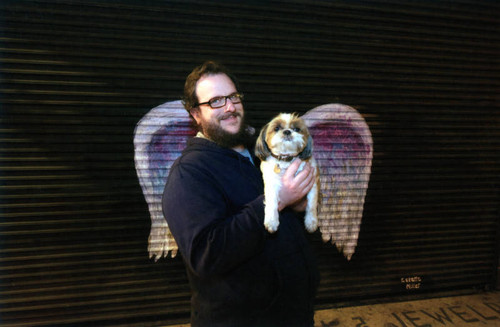 Jim Winstead and Wonton posing in front of a mural depicting angel wings