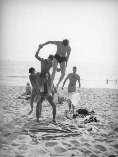 Group of acrobats attempting a human pyramid on the beach