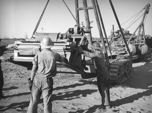 Oil field workers move heavy equipment