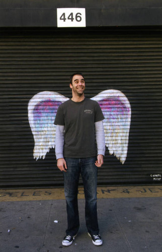 Unidentified man posing in front of a mural depicting angel wings