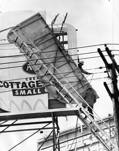 Firemen bring down a flapping sign loosened by wind