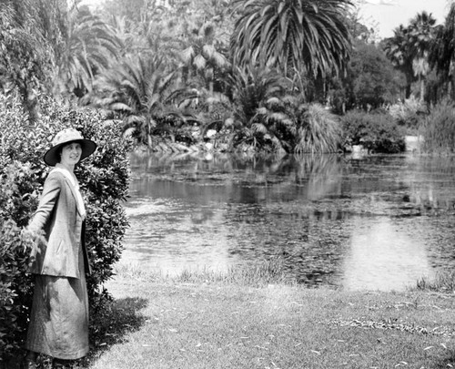Woman wearing hat poses near lake
