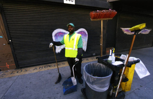 Unidentified custodial worker posing in front of a mural depicting angel wings