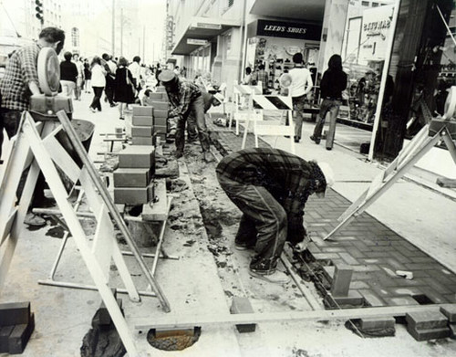 [Construction workers laying bricks on the sidewalks of Market Street]