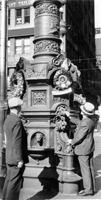 [Two men laying memorial wreaths on Lotta's Fountain]