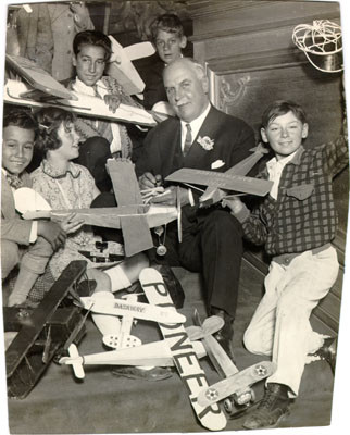 [Mayor James Rolph, Jr. sitting with a group of children holding model airplanes]