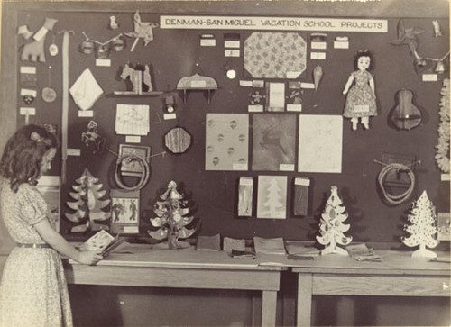 [Student reading in front of a display board at Denman-San Miguel Vacation School, presently known as James Denman Junior High School]