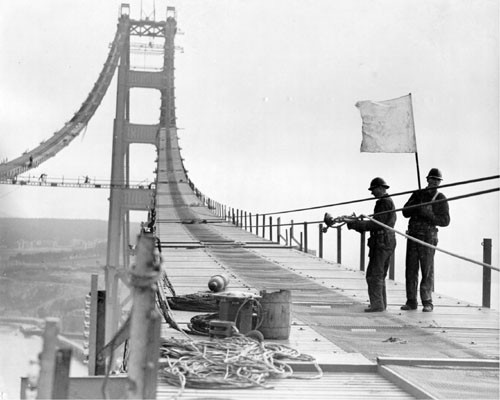 [Workmen laying cables on Golden Gate Bridge catwalk]