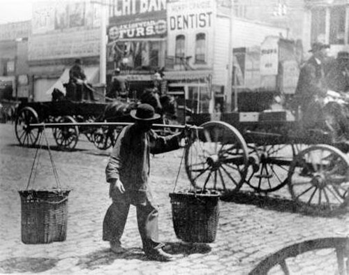 [Man carrying two large baskets]