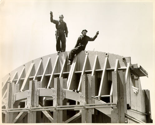 [Two construction workers atop the south tower of the Golden Gate Bridge]