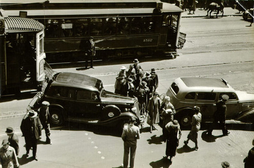 [Pedestrians crossing Market Street between automobile traffic]