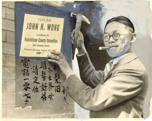 [John H. Wong tacking up a placard to a wall in Chinatown]