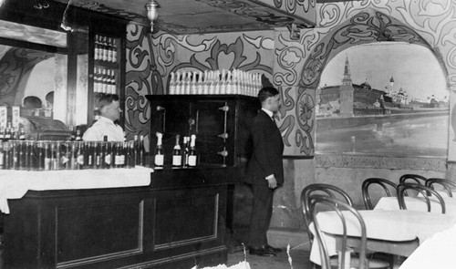 [Bartender and unidentified man looking at a mural on the wall of the New Columbia Inn]