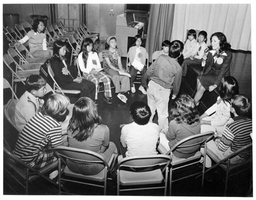 [Unidentified woman talking with a group of Washington Irving School students]