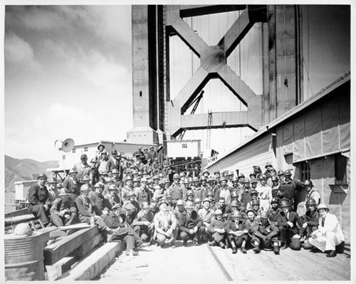 [Workmen being photographed in front of Golden Gate Bridge tower]