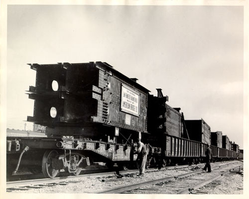 [View of steel being transported on train for San Francisco-Oakland Bay Bridge construction]