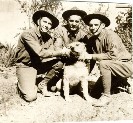 [Three soldiers posing with a dog during Army Day in San Francisco]