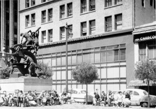 [Group of people sitting around the base of the Donahue Monument, also known as the Mechanics Monument, on Market Street]