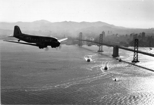 [Airliner flies past Bay Bridge]